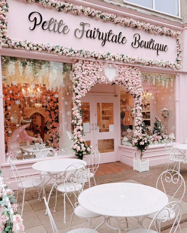 a pink store front with white tables and chairs