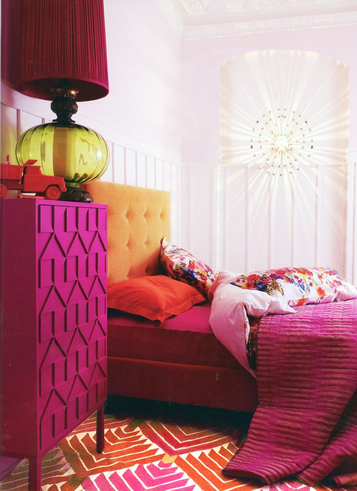 a bedroom with a pink bed and orange pillows