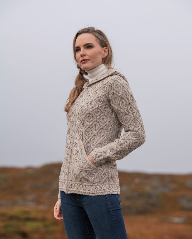 a woman standing on top of a hill wearing a sweater