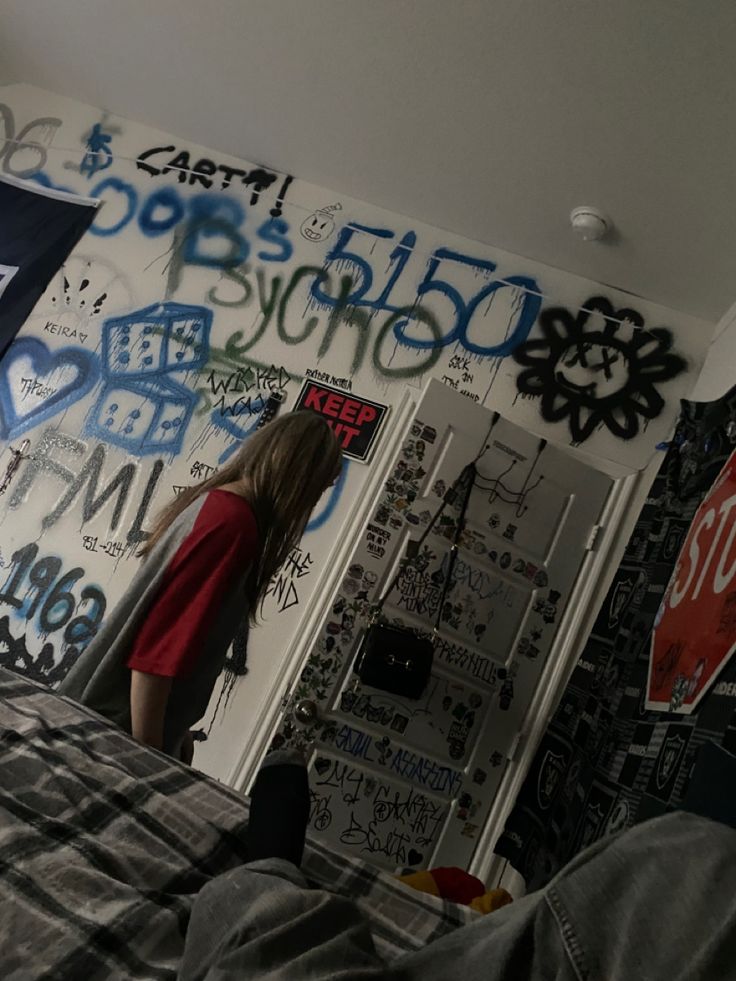 a person standing in front of a wall with graffiti on it and writing all over the walls