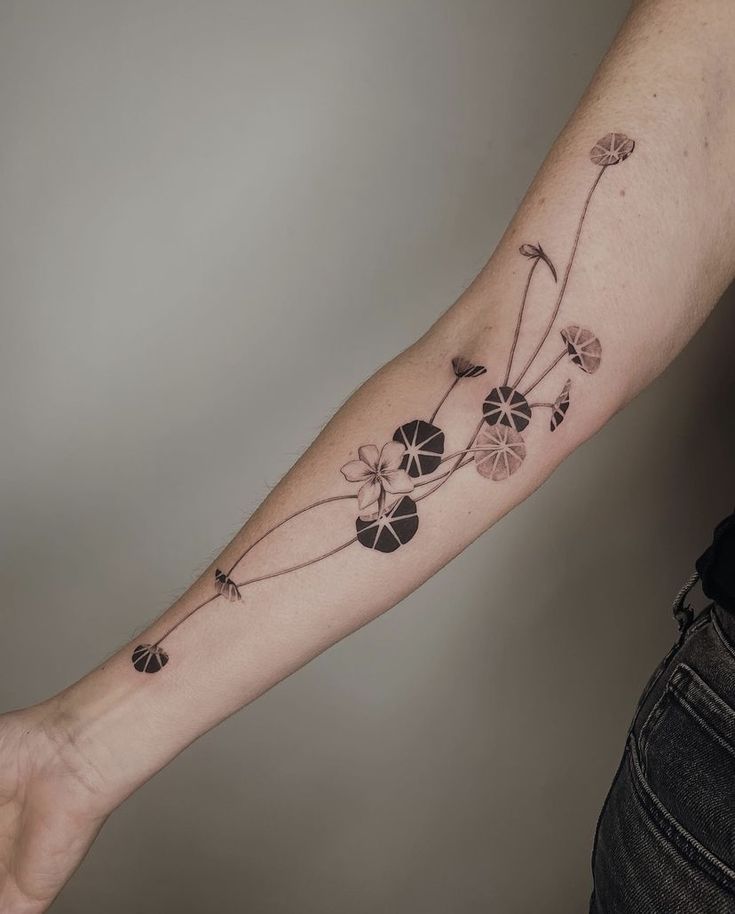 a woman's arm with flowers and leaves tattooed on the left side of her arm