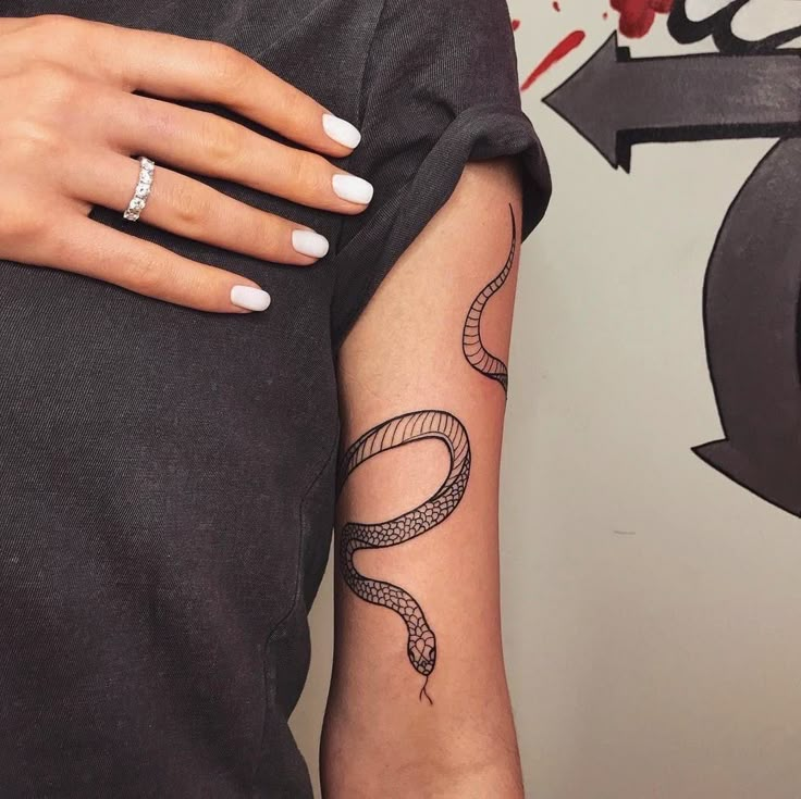 a woman's arm with a snake tattoo on it