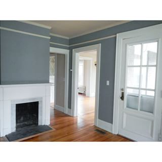 an empty living room with hard wood floors and white trim on the fireplace mantel