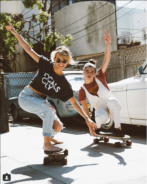 two people riding skateboards on the street