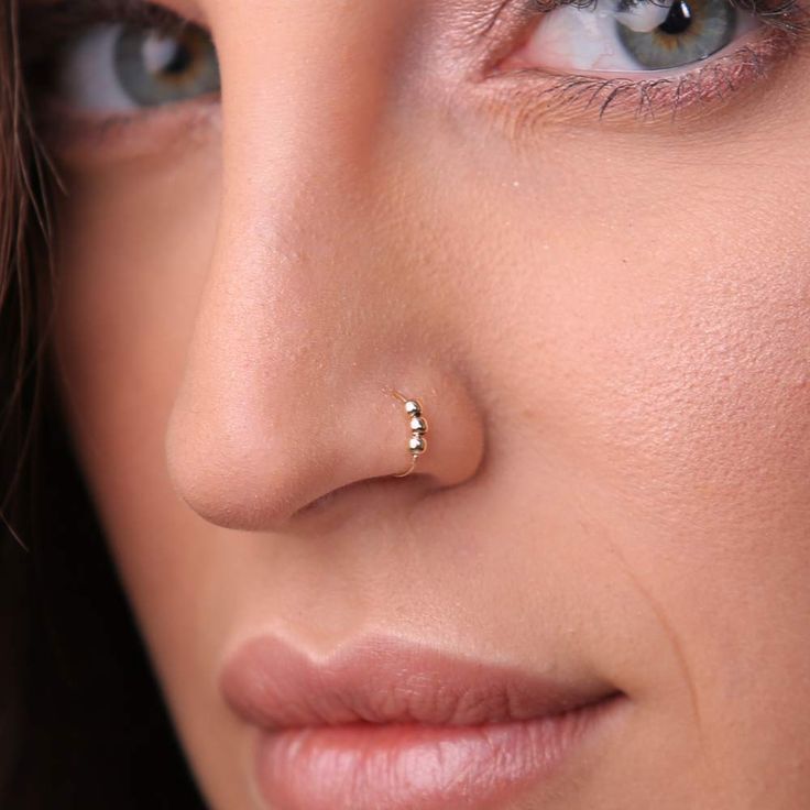 a close up of a woman with a nose piercing on her nose and blue eyes