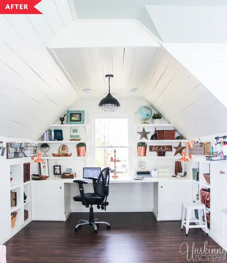 a home office with white walls and wooden flooring in an atticed room that also has shelving on the wall