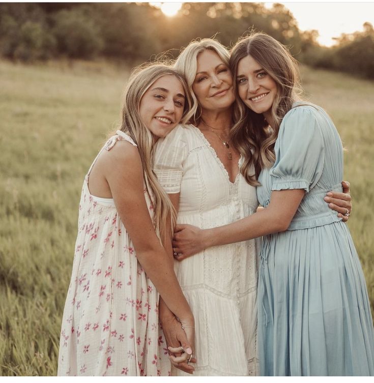 three girls hugging each other in a field