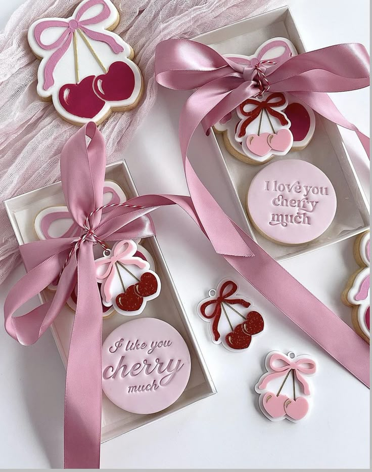 two decorated cookies in boxes with pink ribbons