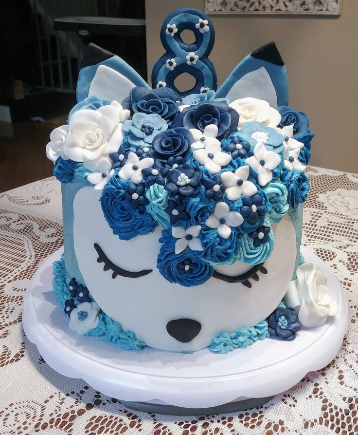 a blue and white birthday cake with flowers on the top is decorated like an animal