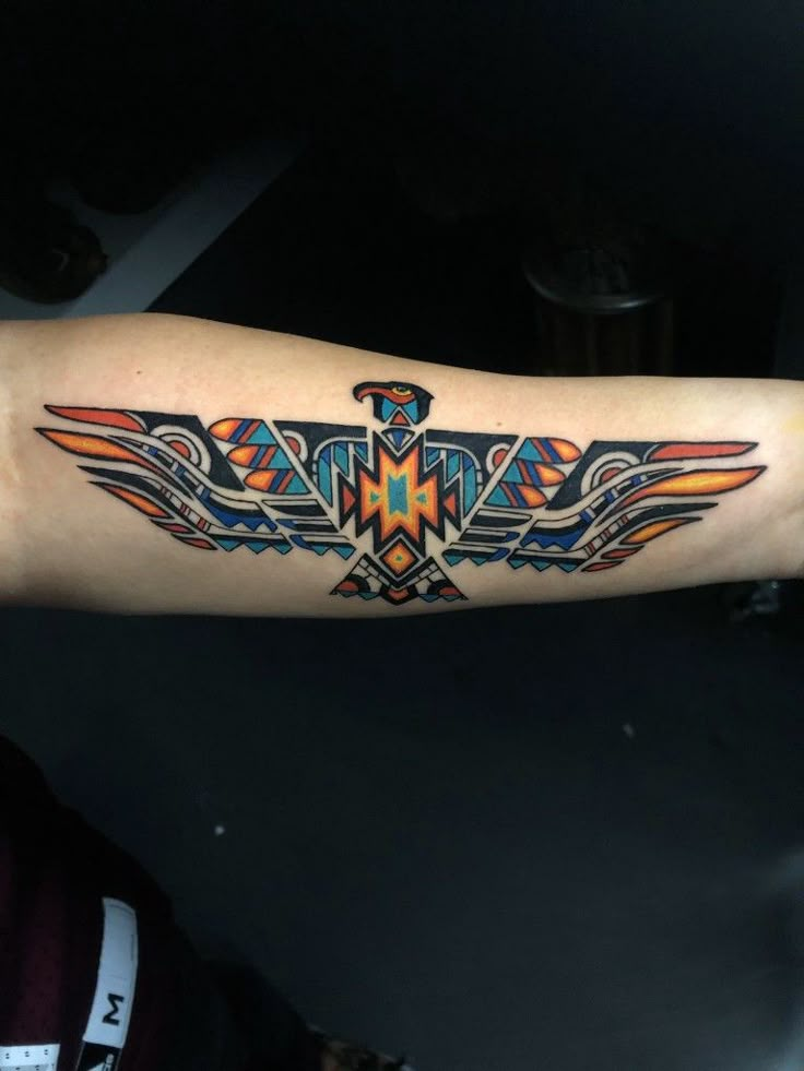 a colorful tattoo on the arm of a man with an eagle and geometrical design