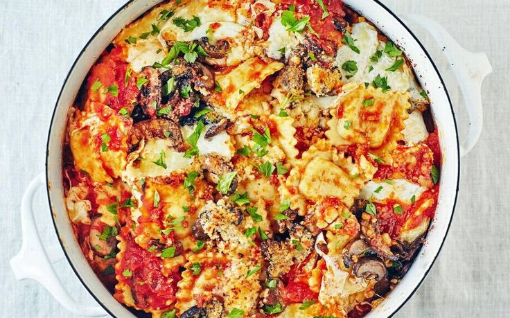 a pan filled with pasta and vegetables on top of a white tablecloth covered table