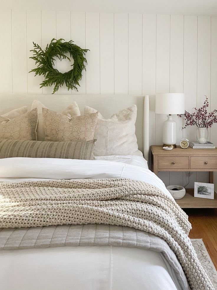 a bed with white linens and pillows in a bedroom next to a wooden nightstand