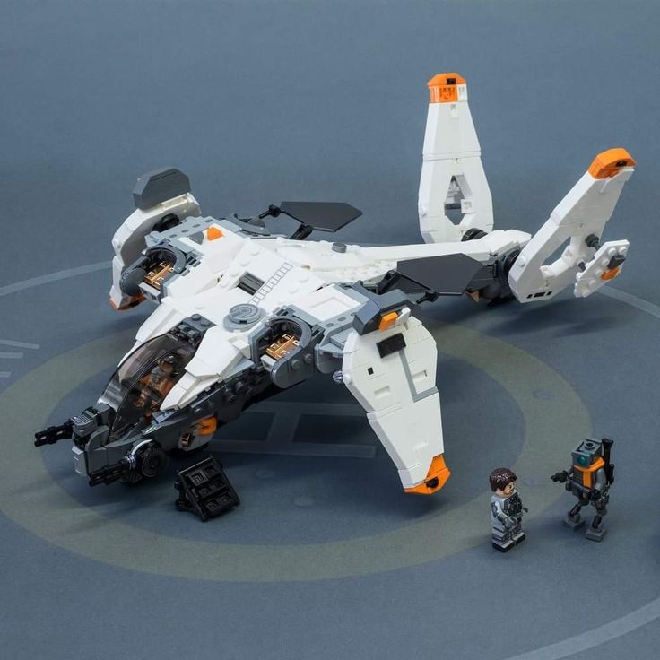 a lego star wars fighter jet is shown with two small figurines on the ground