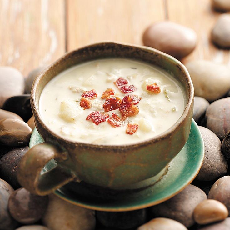 a bowl of soup with bacon in it sitting on top of some rocks and pebbles