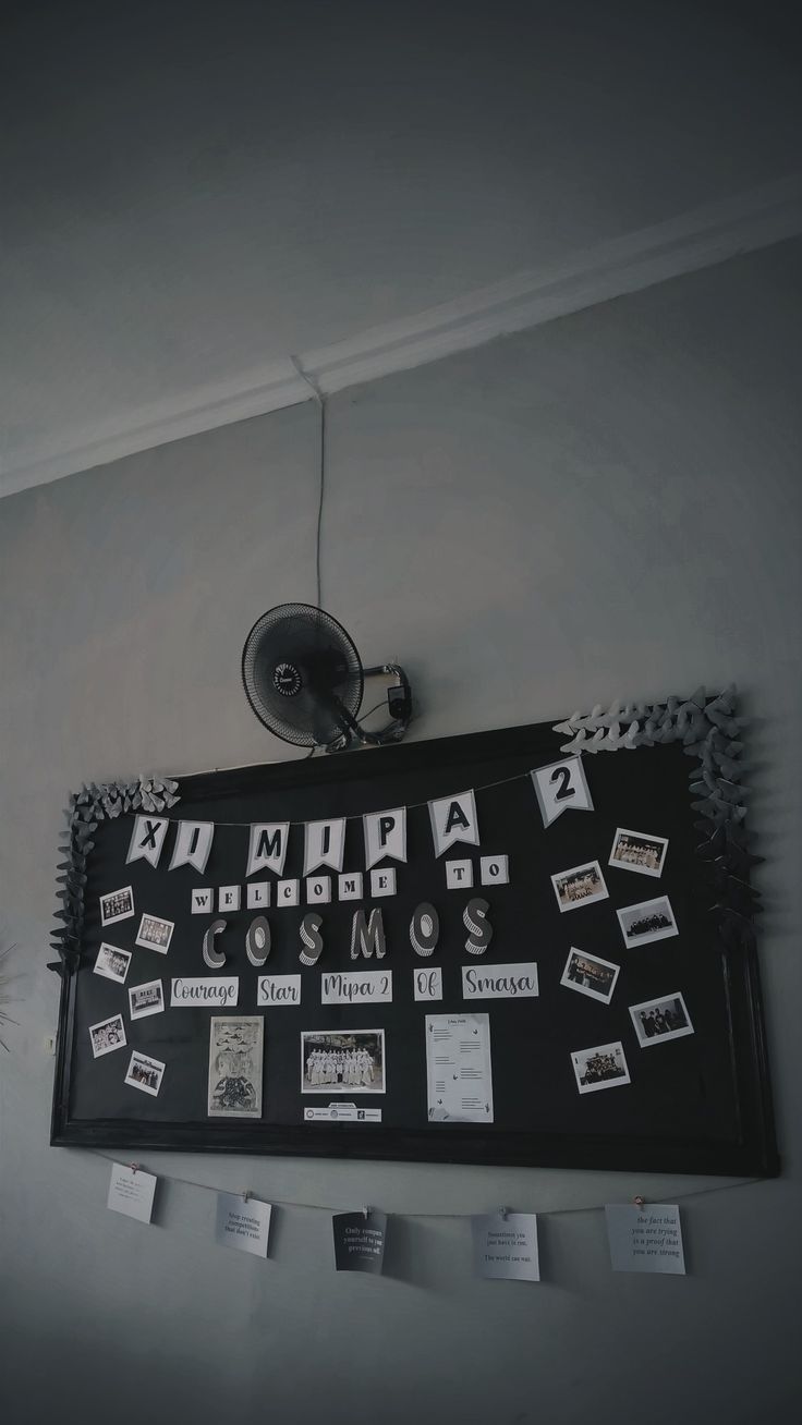 a black and white photo hanging on the wall above a bulletin board with magnets