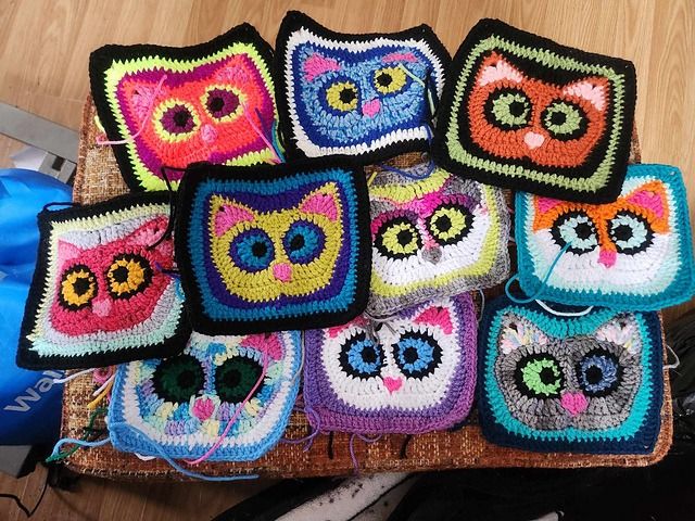 there are many crocheted owl squares on the table