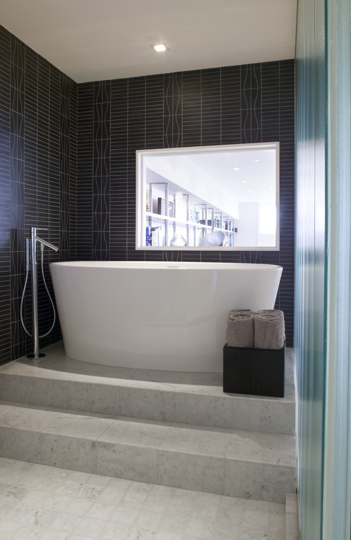 a white bath tub sitting on top of a set of steps next to a window