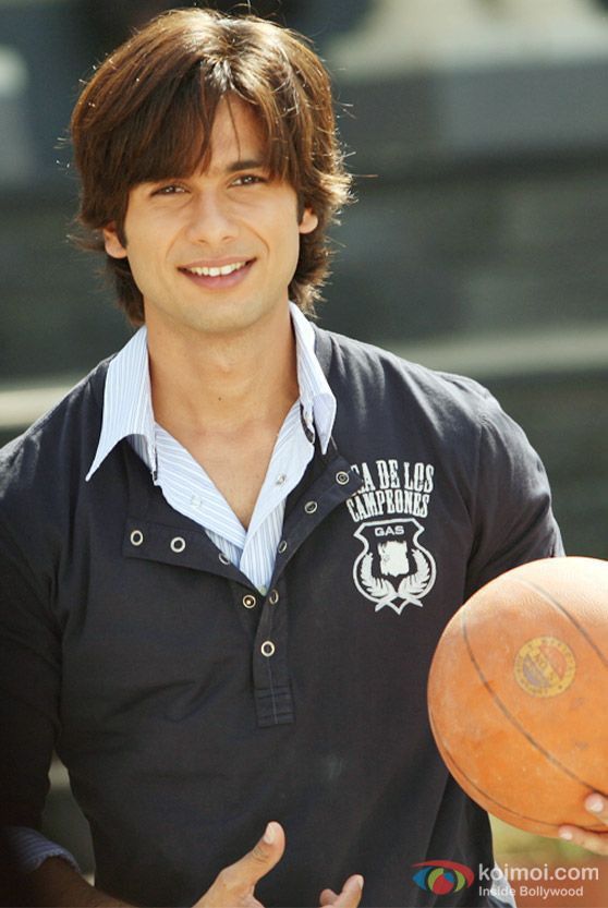 a man holding a basketball in his right hand and smiling at the camera while standing next to him