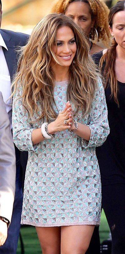 a woman with long hair is standing in front of other people and clapping her hands