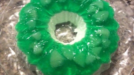 there is a green ring shaped cake on the plate with plastic wrapper around it