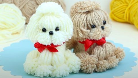 two stuffed dogs sitting next to each other in front of some balls of knitting yarn