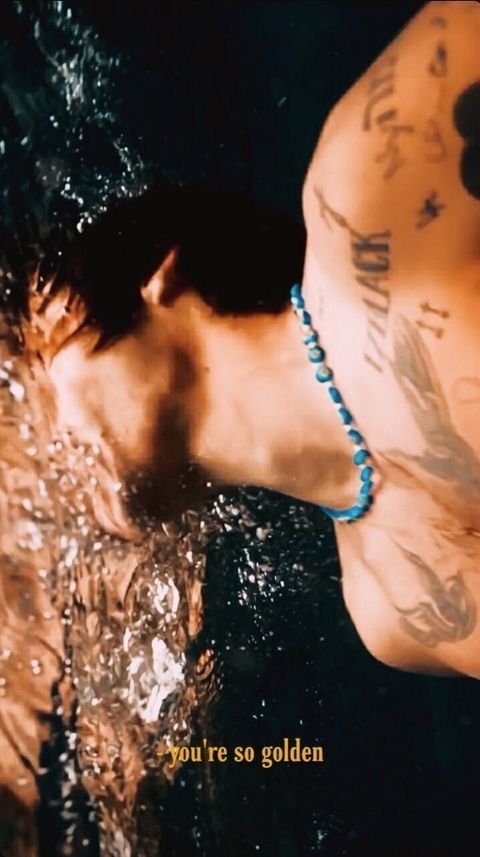 a man swimming in the water with tattoos on his chest and arm, wearing a blue bracelet