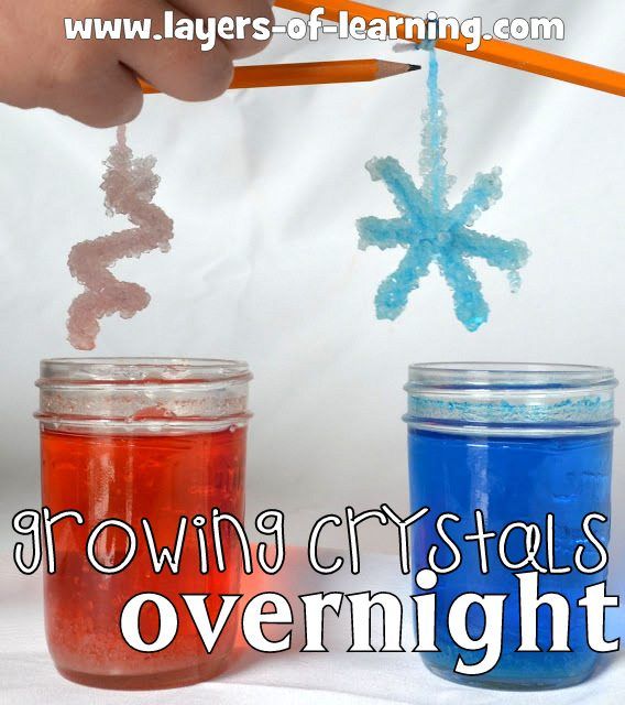 two jars filled with colored liquid and one has a snowflake on it, while the other holds a pencil