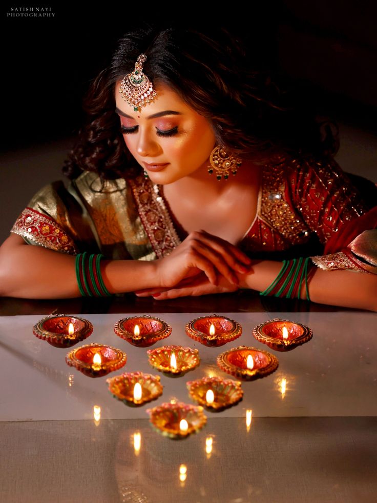 a woman sitting at a table with candles in front of her and looking down on the ground