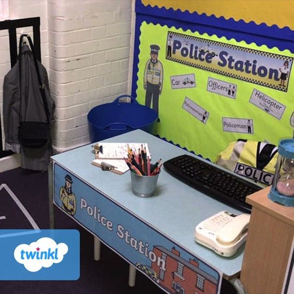 a police station desk with a keyboard and some school supplies on it, in front of a bulletin board