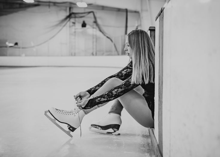 black and white photograph of a woman sitting on the floor with her legs crossed, leaning against a wall