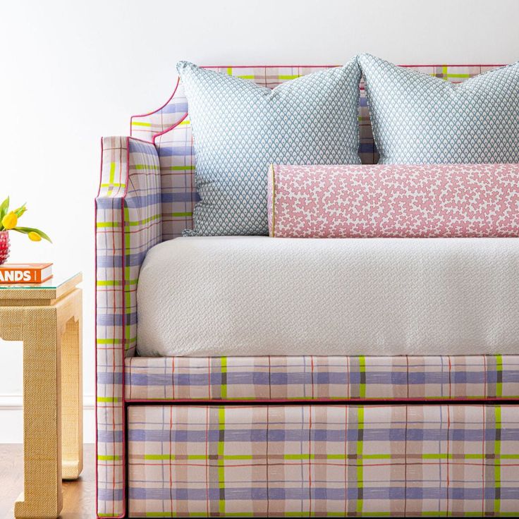 a couch with pillows on top of it next to a small table and potted plant