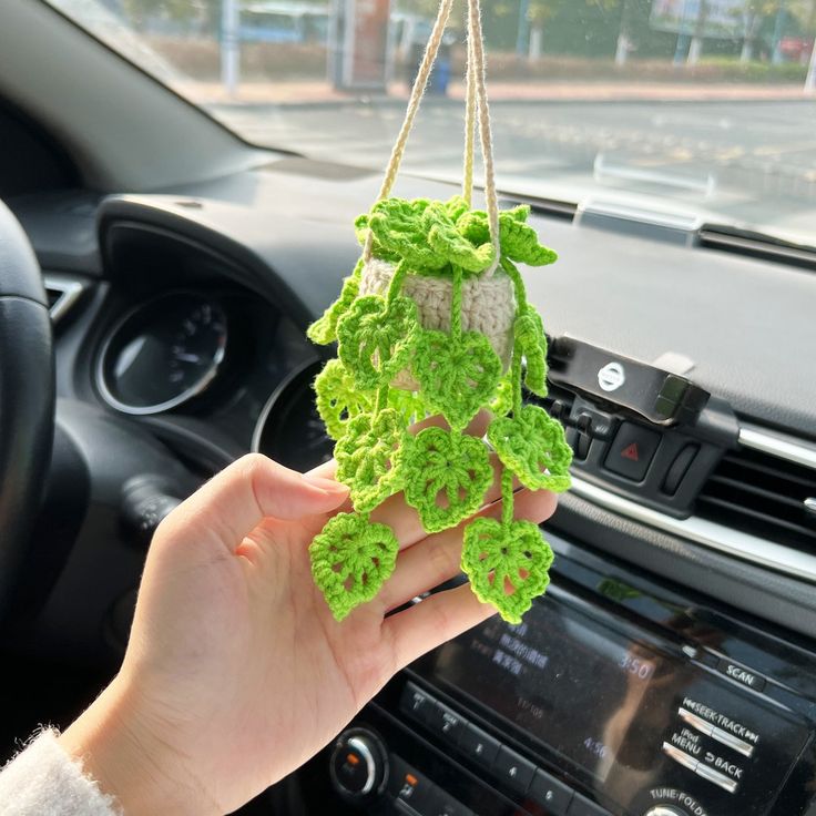 a person holding up a green item in their hand next to a car radio and steering wheel