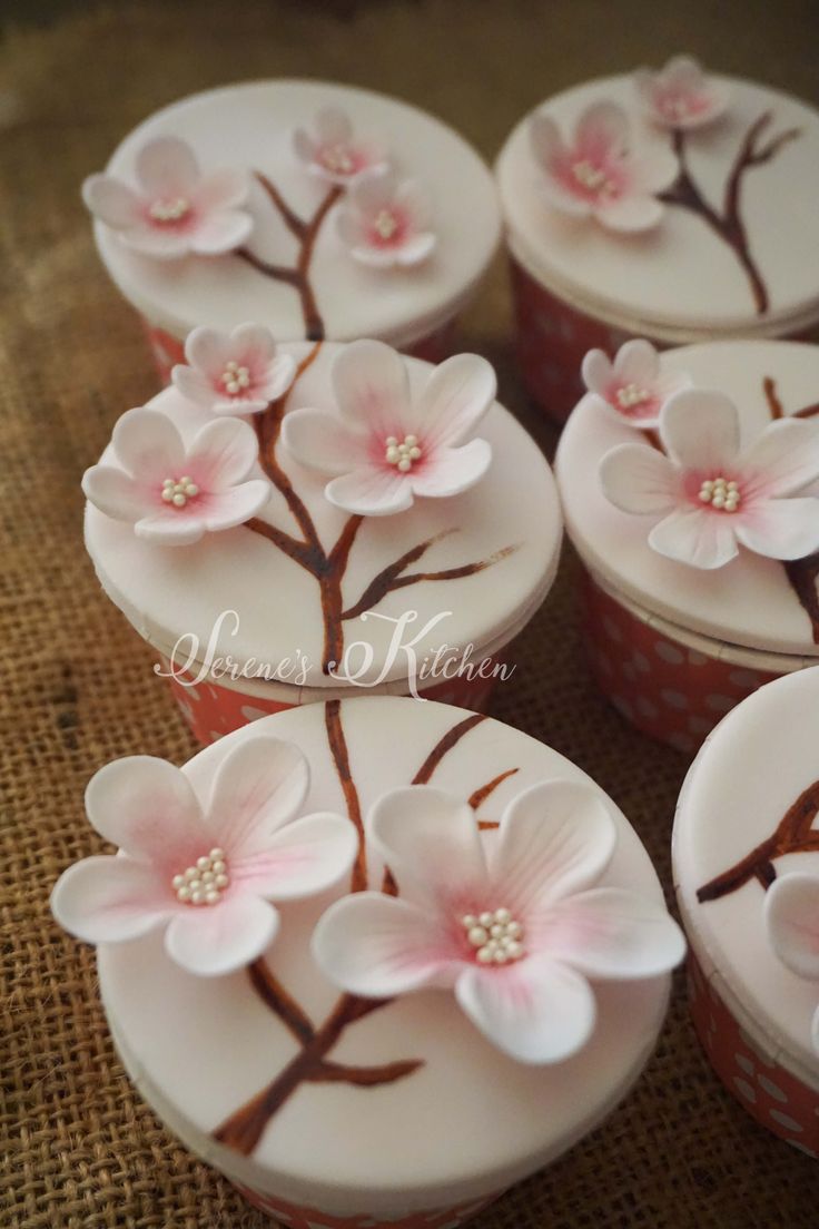 several cupcakes decorated with pink flowers and leaves