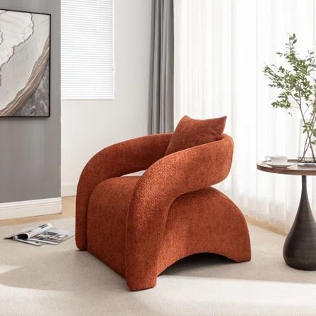 an orange chair sitting on top of a white floor next to a table with a vase