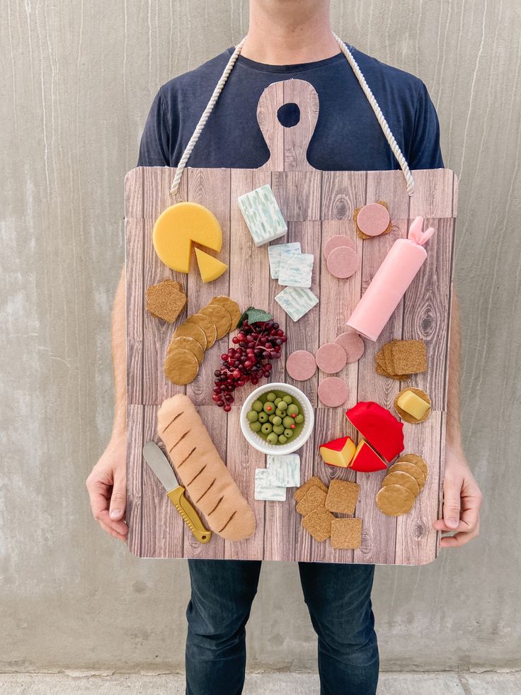 a man is holding a board with food on it that includes meats, cheeses and crackers