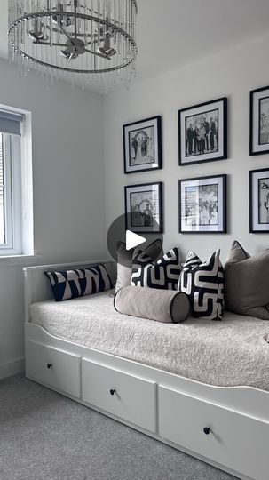 a white day bed sitting under a chandelier next to a window with pictures on the wall