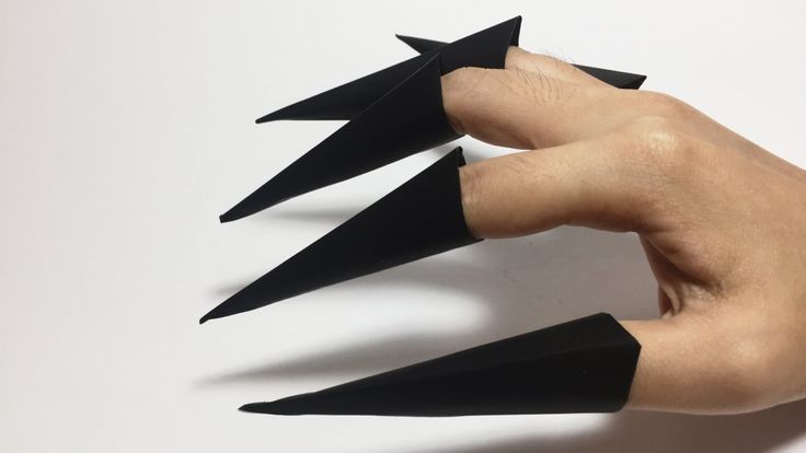 a person's hand is holding three pointed black objects in the shape of an arrow