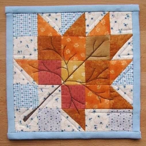 an orange and yellow leaf on top of a blue quilted table cloth with white polka dots