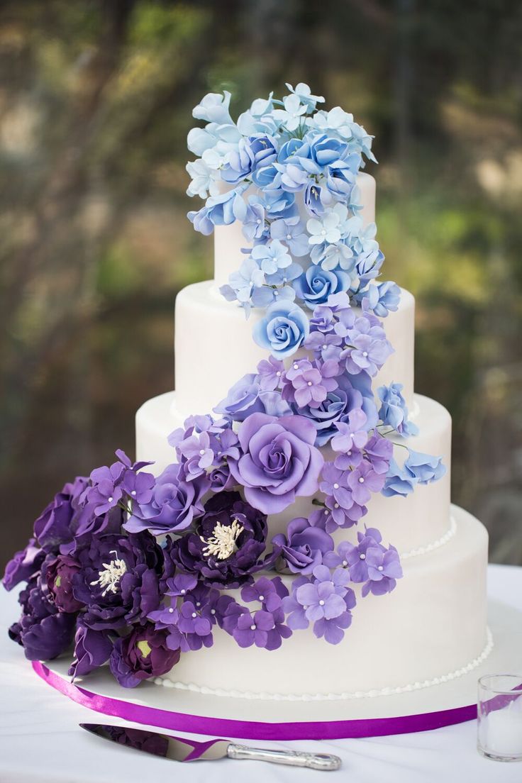 a wedding cake decorated with purple and blue flowers