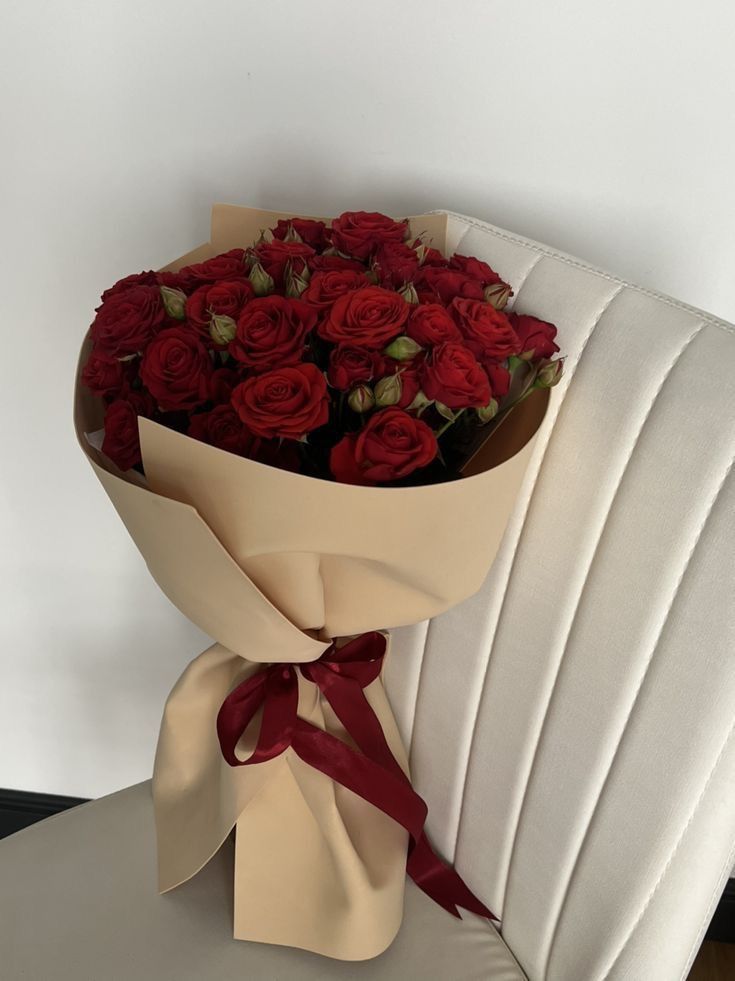 a bouquet of red roses sitting on top of a white chair