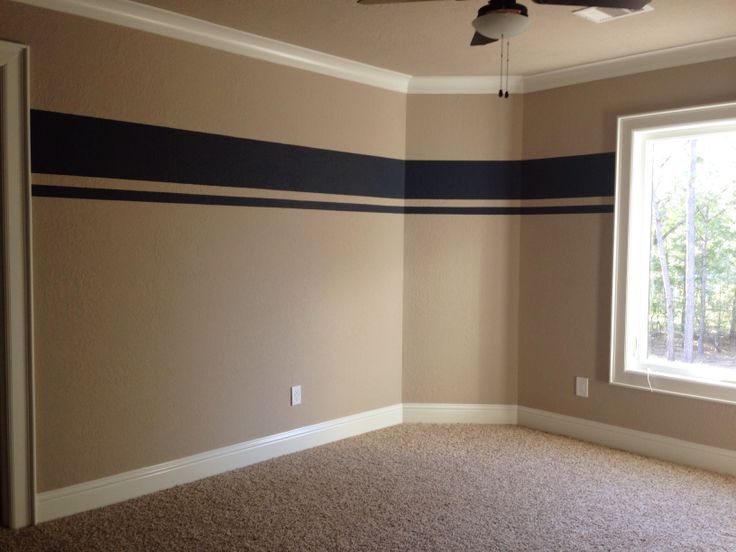 an empty room with carpet, ceiling fan and large window in the corner on the far wall