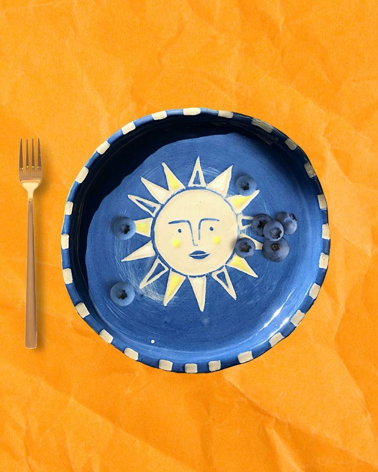 a blue plate with a face painted on it next to a fork