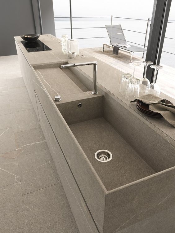 an image of a sink in the middle of a counter top with wine glasses and utensils on it