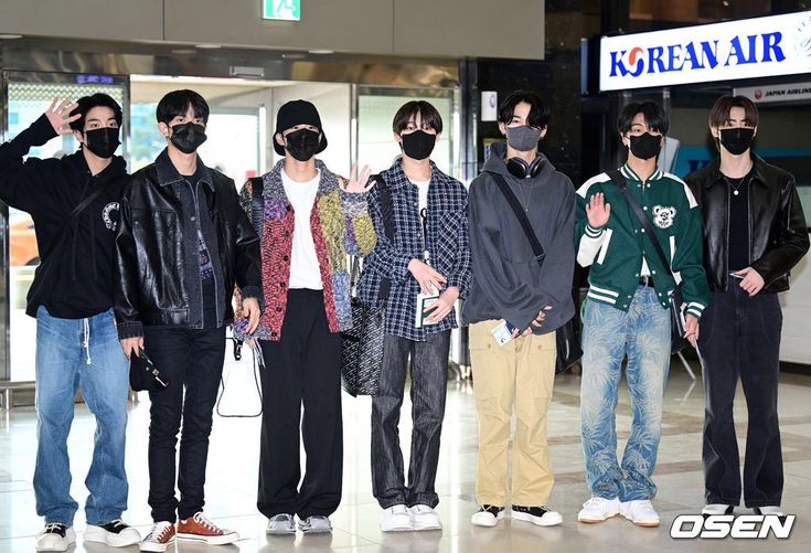 four men wearing masks standing in front of an airport lobby door with their hands on their hips