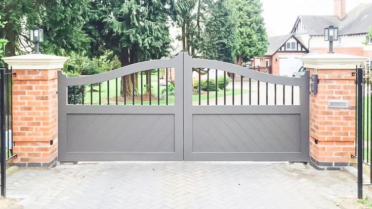 an iron gate with brick pillars and gates on either side, leading to a driveway