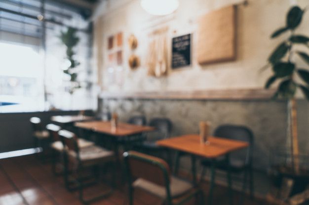 blurry image of tables and chairs in a restaurant with wood flooring on the walls