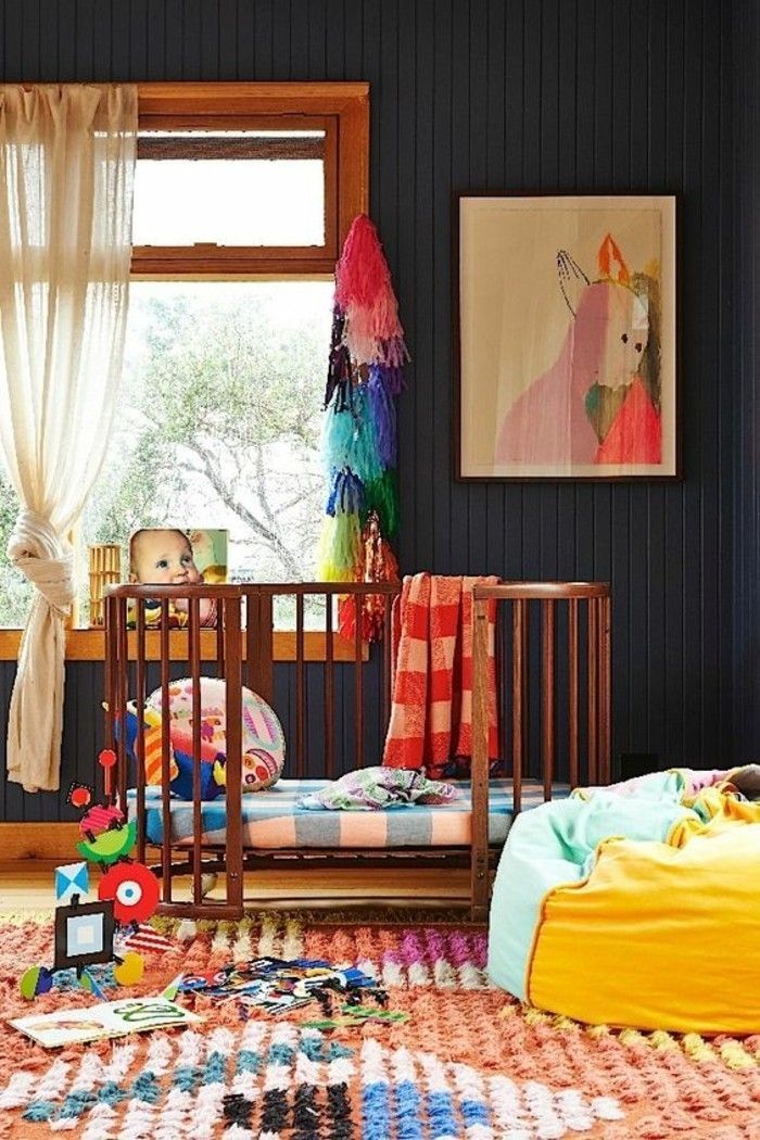 a child's room with a crib and toys on the floor in front of a window