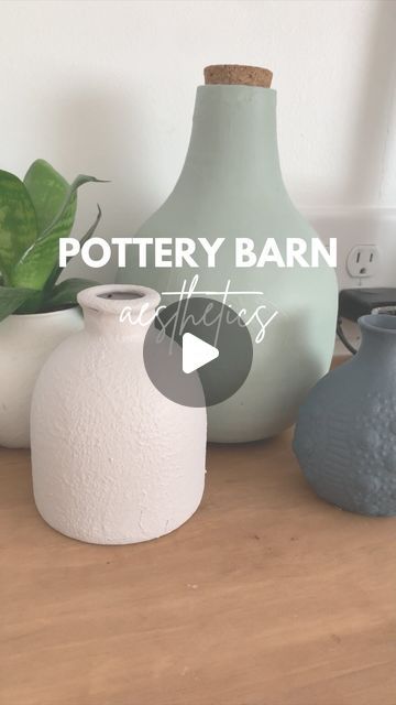 three vases sitting on top of a wooden table next to a potted plant