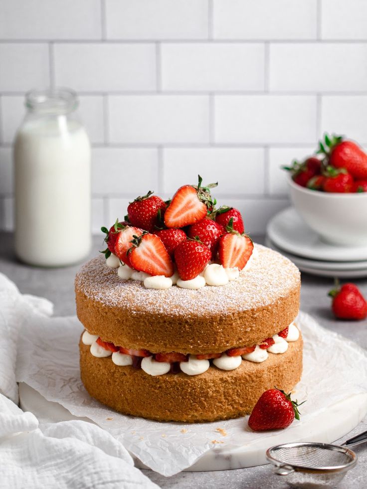 there is a cake with strawberries on top and white frosting next to it