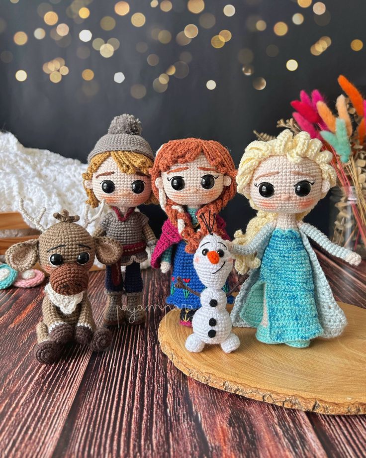 three knitted dolls are standing next to each other on a wooden table with lights in the background